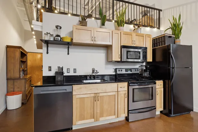 a kitchen with stainless steel appliances granite countertop a sink a stove a refrigerator and cabinets