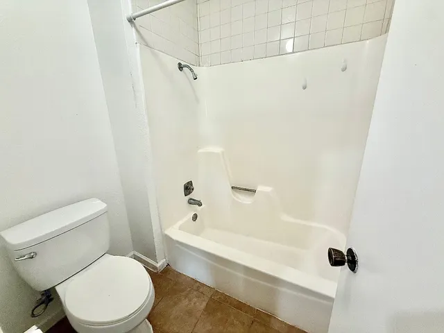 a white toilet sitting next to a bath tub