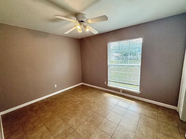 en empty room with windows and chandelier fan