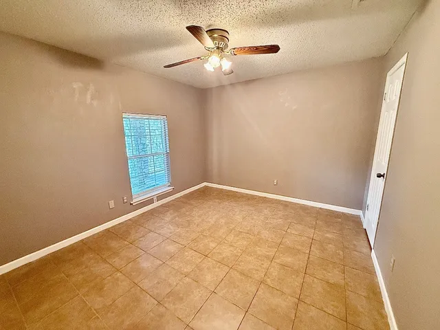 an empty room with windows and fan