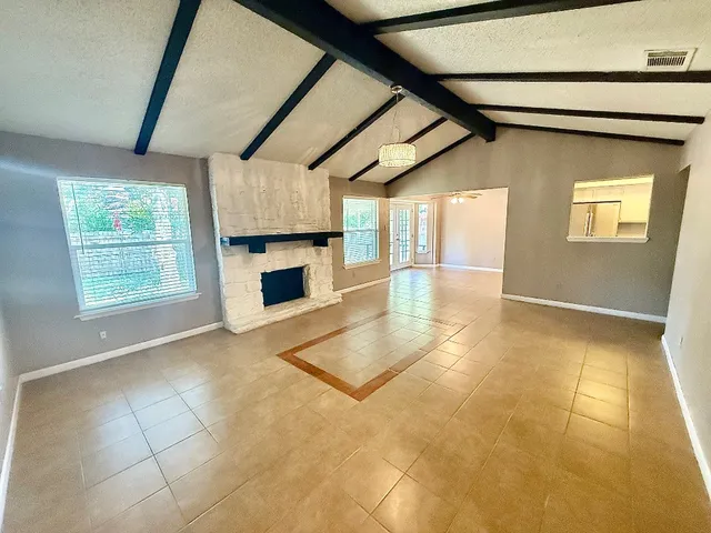 a view of an empty room with a fireplace and a window