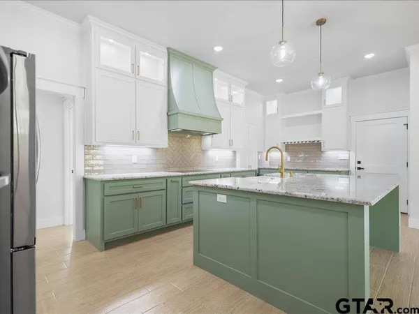 a kitchen with kitchen island granite countertop a sink a counter space appliances and cabinets