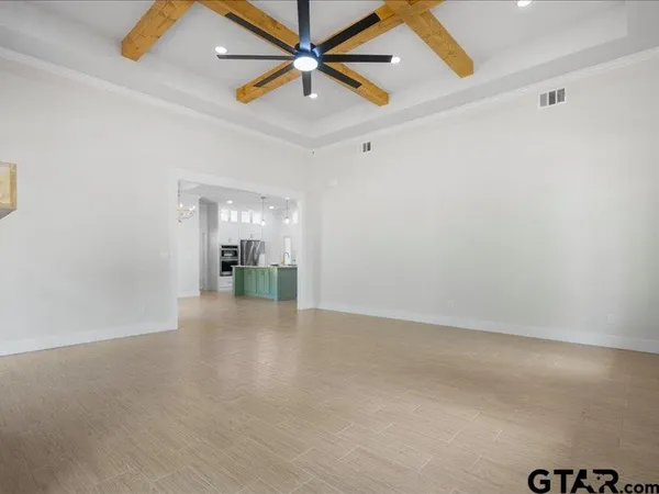 an empty room with chandelier fan and windows