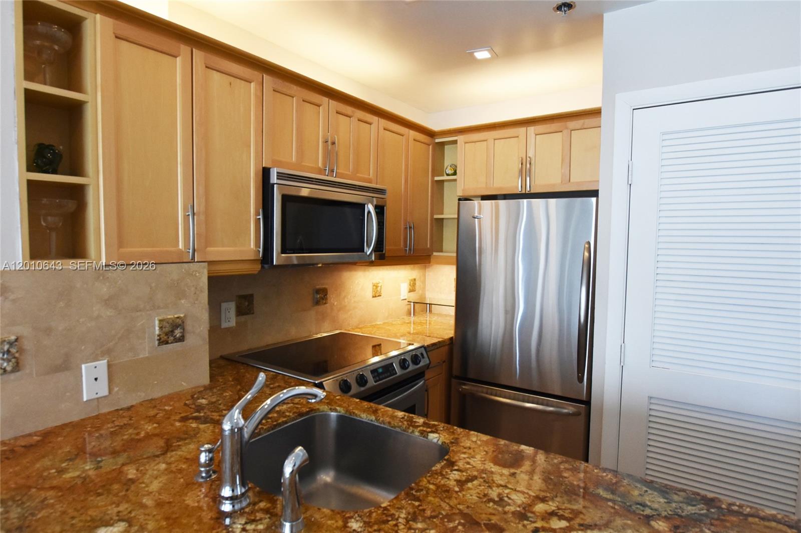 540 Brickell Key Drive, Unit PH1812 Miami, FL 33131 - Photo 5 of 29 a kitchen with stainless steel appliances granite countertop a refrigerator a stove and a sink with wooden floor