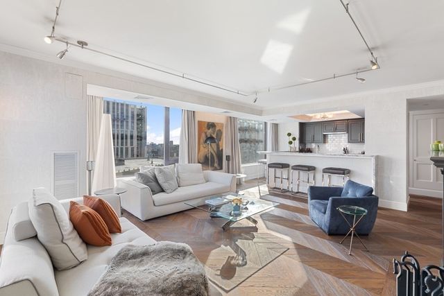 a living room with furniture a rug and kitchen view