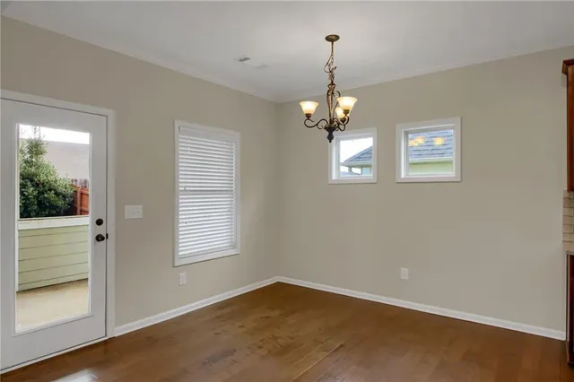 an empty room with wooden floor mirror and windows