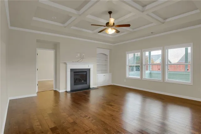 a view of an empty room with chandelier fan and a fireplace
