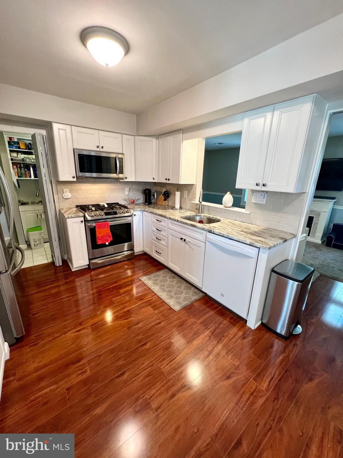 6256 Madison Court Bensalem, PA 19020 - Photo 3 of 14 a kitchen with stainless steel appliances granite countertop a stove top oven a sink dishwasher and white cabinets with wooden floor