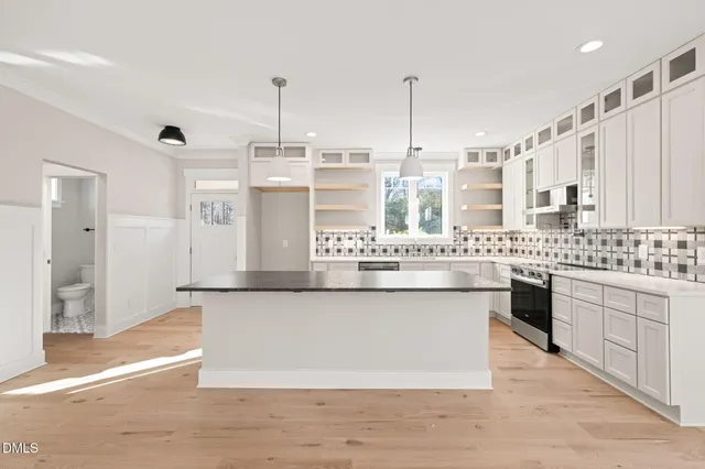 a large kitchen with a large counter top a sink stainless steel appliances and cabinets