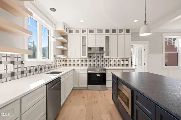a large kitchen with a large counter top a sink stainless steel appliances and cabinets