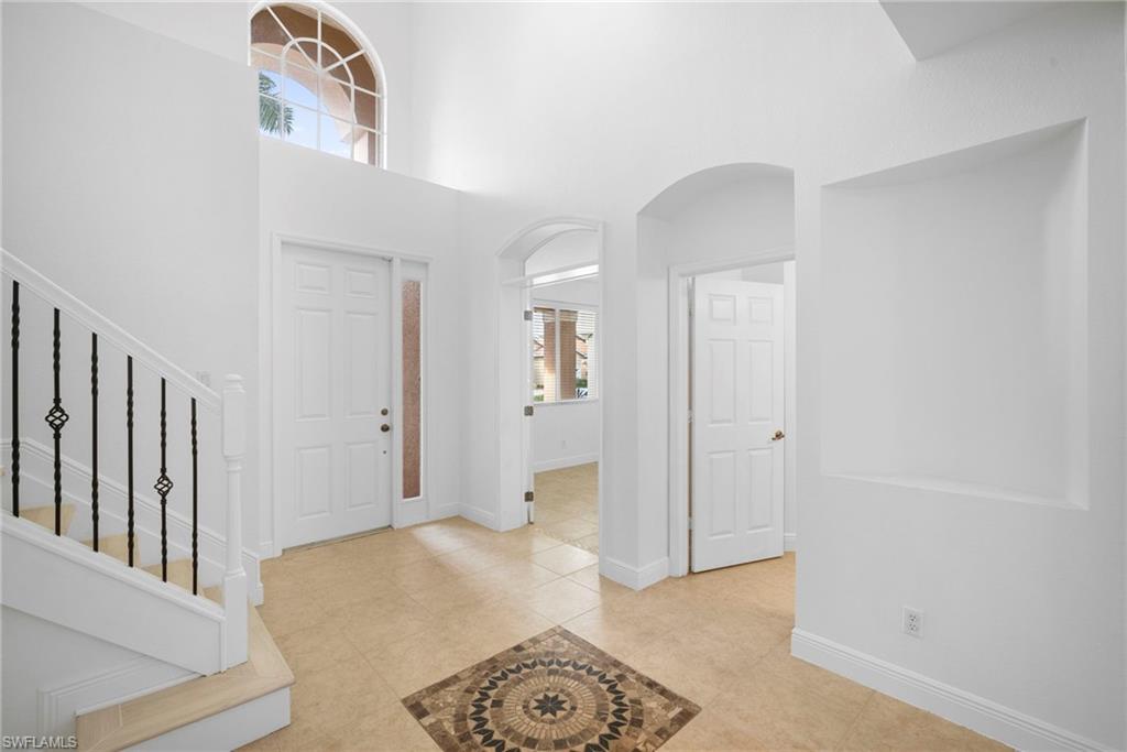 8286 Sumner Avenue, Unit 1 Fort Myers, FL 33908 - Photo 2 of 13 Foyer with arched walkways, a towering ceiling, light tile patterned flooring, and stairway