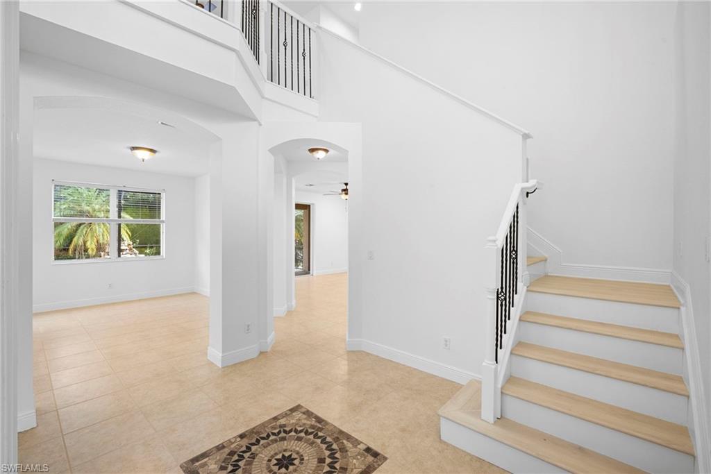 8286 Sumner Avenue, Unit 1 Fort Myers, FL 33908 - Photo 3 of 13 Stairway with arched walkways, a high ceiling, a ceiling fan, and tile patterned flooring