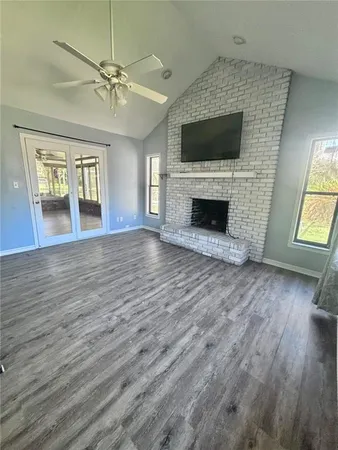 an empty room with wooden floor fireplace and windows