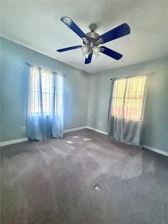 an empty room with windows and fan