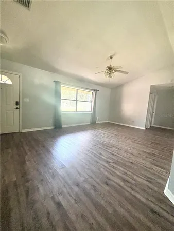 an empty room with wooden floor and windows