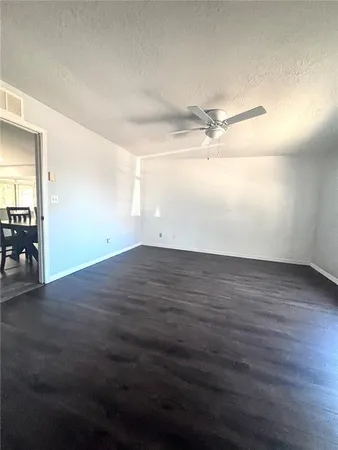 an empty room with wooden floor fan and windows