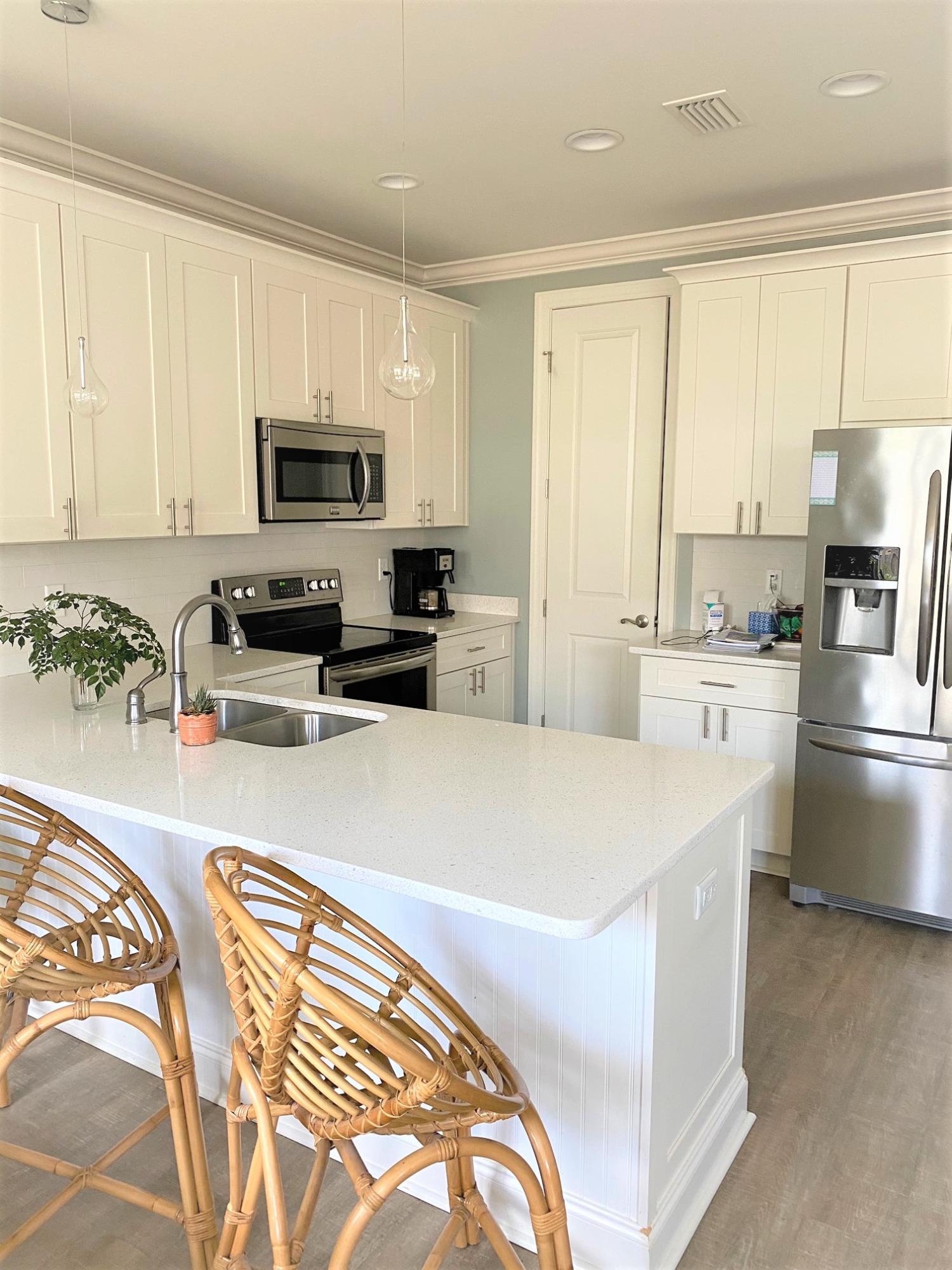 64 Hatton Court Santa Rosa Beach, FL 32459 - Photo 6 of 37 a large white kitchen with kitchen island a sink a stove a microwave a counter top space and cabinets