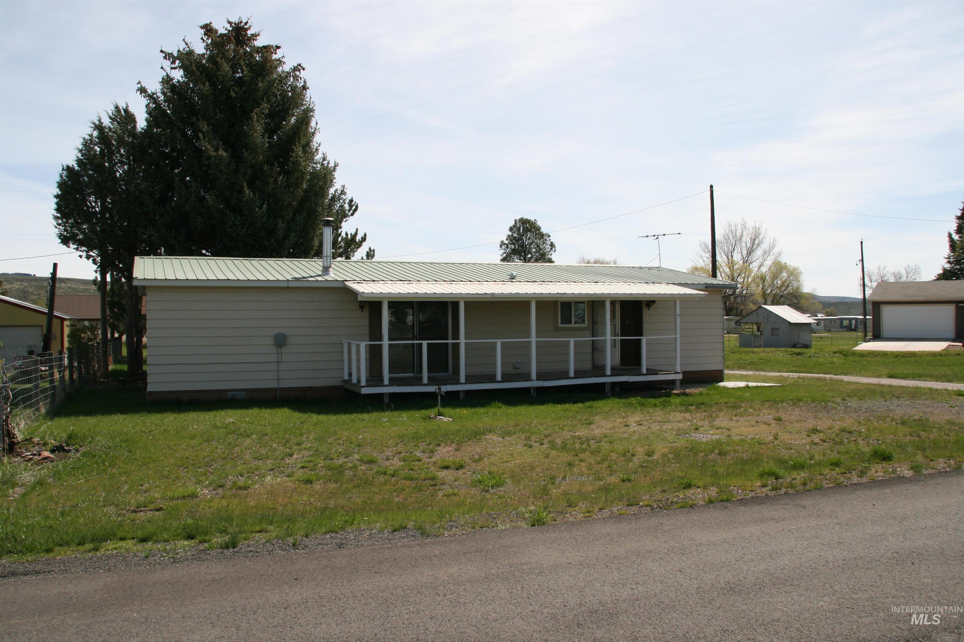 Back of house featuring a garage, a metal roof, a yard, and a sunroom