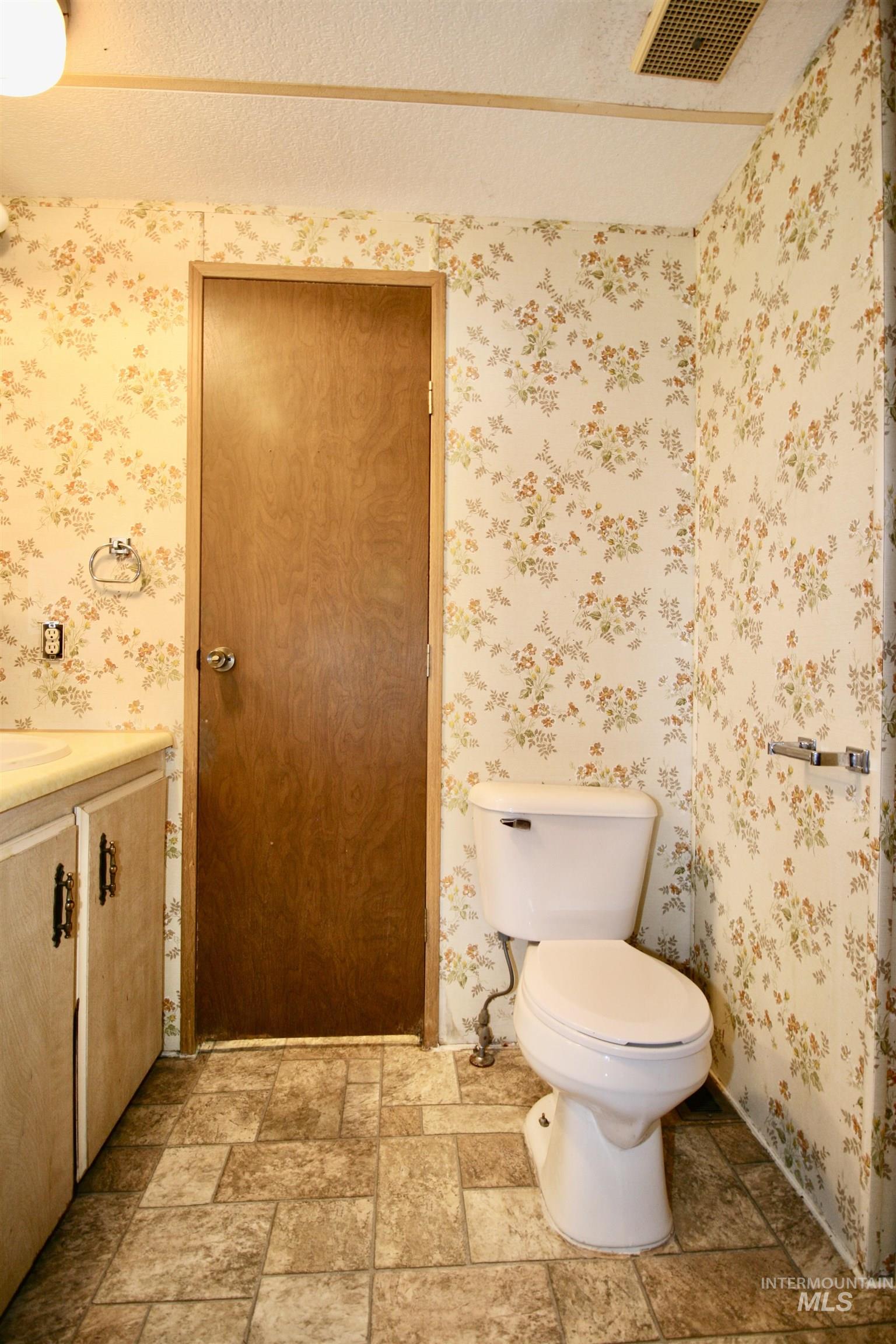 500 Somerville Street Jordan Valley, OR 97910 - Photo 23 of 35 Half bathroom with vanity, a textured ceiling, and light stone finish floors
