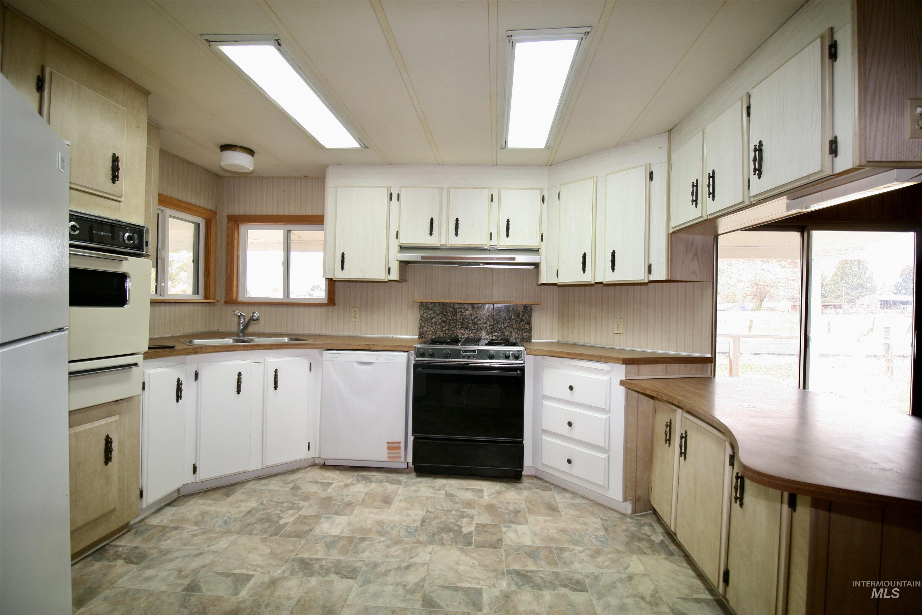 500 Somerville Street Jordan Valley, OR 97910 - Photo 31 of 35 Kitchen with white appliances, stone finish flooring, a warming drawer, light countertops, and under cabinet range hood
