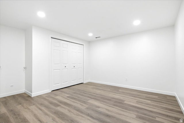 1676 East 11245 South Sandy, UT 84092 - Photo 28 of 34 Spacious room featuring wood-finish flooring, recessed lighting, white walls, white baseboards, and bi-fold closet doors