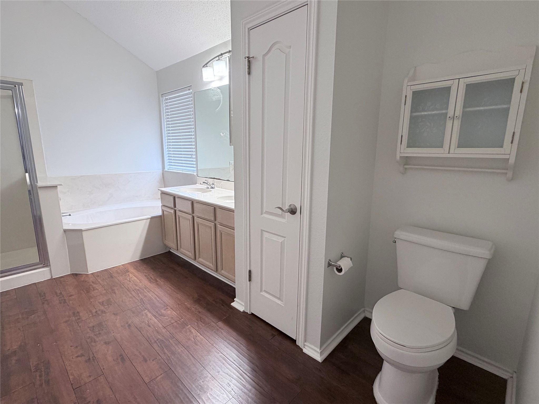 20809 Pacers Gait Lane Pflugerville, TX 78660 - Photo 15 of 23 Full bathroom with lofted ceiling, a bath, vanity, dark wood-style floors, and a stall shower
