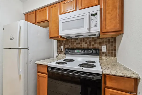 a kitchen with stainless steel appliances granite countertop a stove and a refrigerator with white cabinets