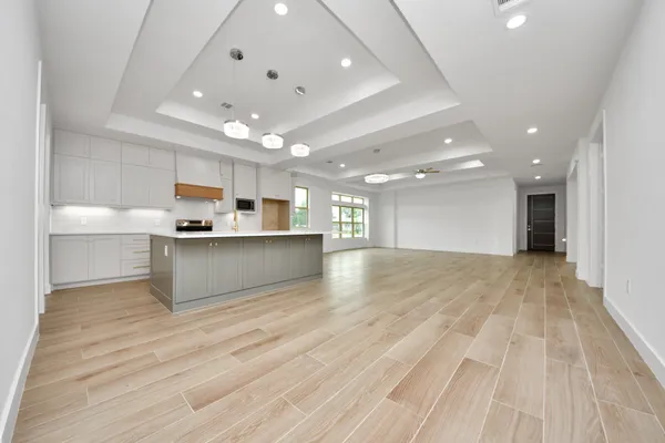 a view of kitchen with kitchen island a sink wooden floor and a refrigerator