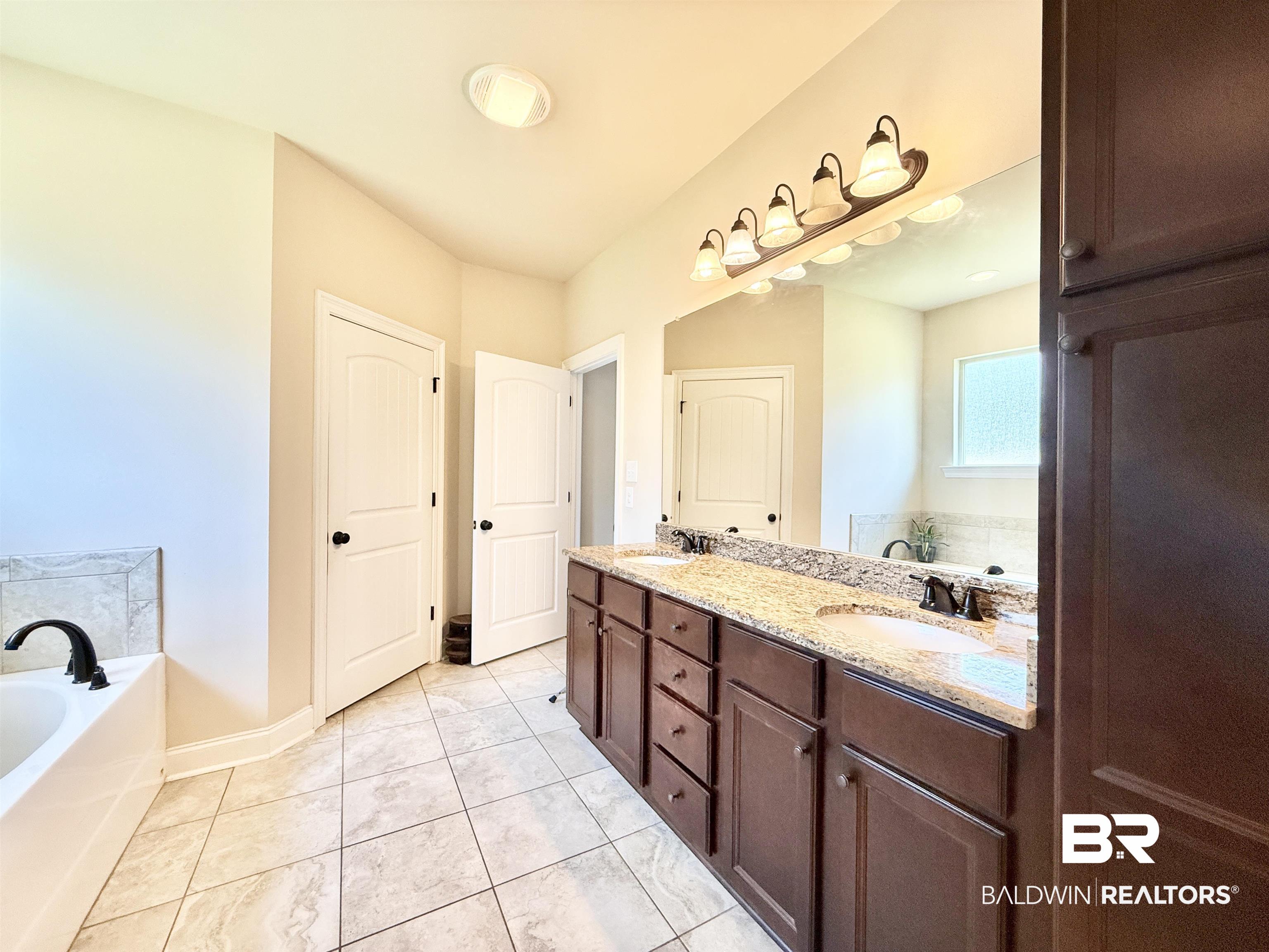 7011 Rocky Rd Loop Gulf Shores, AL 36542 - Photo 26 of 66 Full bath featuring a bath, double vanity, and light tile patterned floors