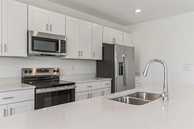 a kitchen with stainless steel appliances granite countertop a sink a stove and microwave
