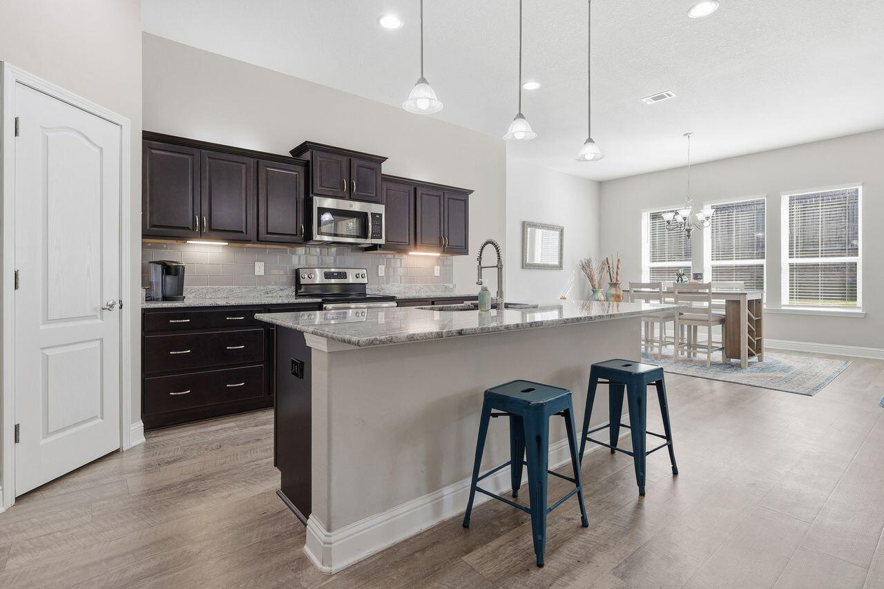 3025 Crown Creek Circle Crestview, FL 32539 - Photo 11 of 46 a kitchen with stainless steel appliances granite countertop a stove top oven a sink a refrigerator white cabinets and wooden floor