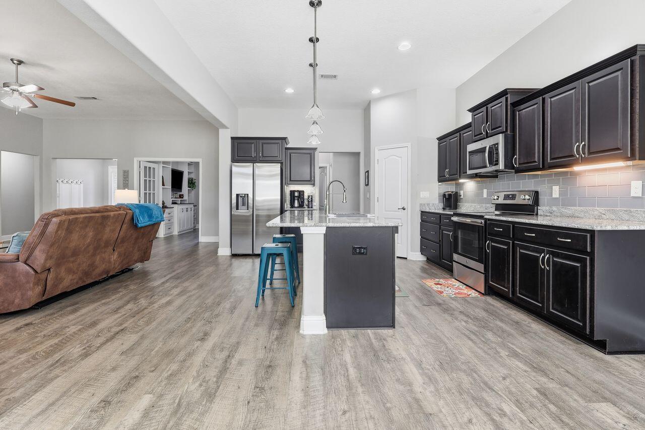 3025 Crown Creek Circle Crestview, FL 32539 - Photo 16 of 46 a large kitchen with stainless steel appliances granite countertop a stove a sink dishwasher and a refrigerator with wooden floor
