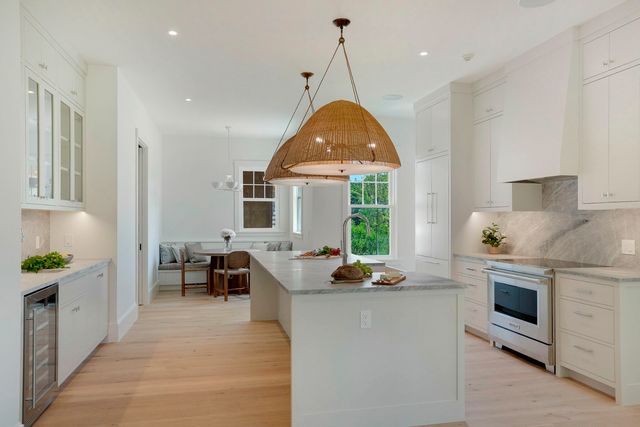 a open kitchen with stainless steel appliances granite countertop a stove oven a sink a dining table and chairs with wooden floor