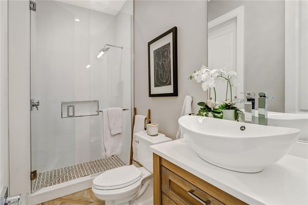 1919 Manchester Circle Naples, FL 34109 - Photo 19 of 45 a bathroom with a sink a toilet a mirror and shower