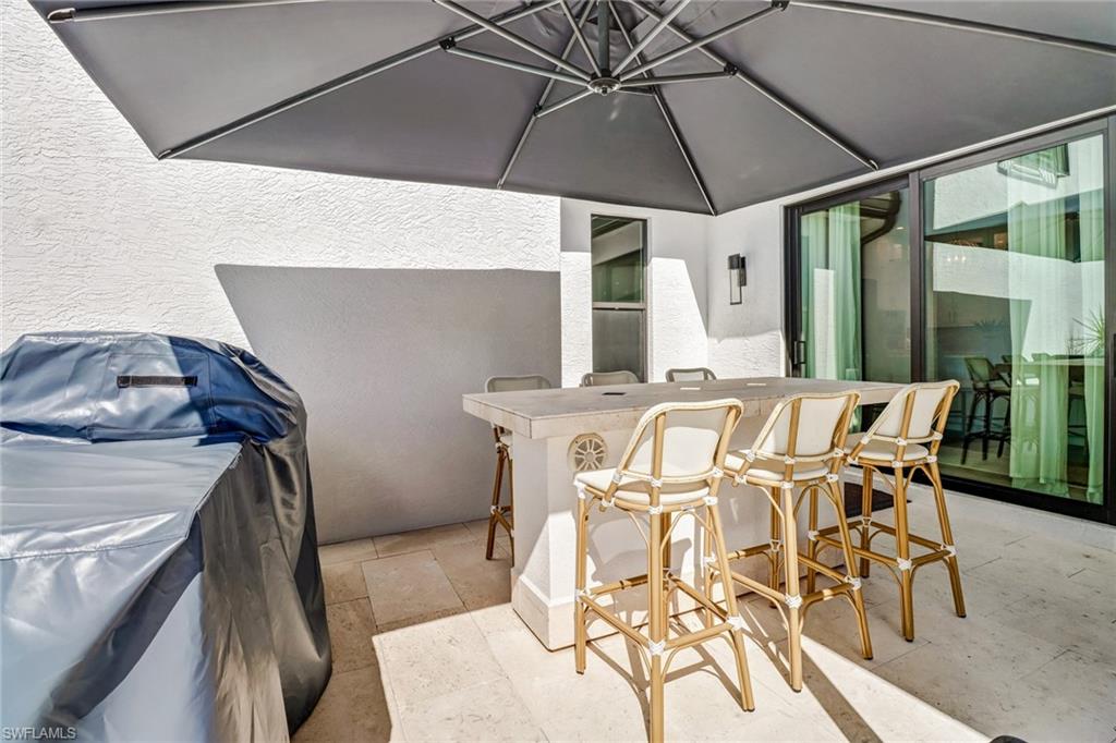 1919 Manchester Circle Naples, FL 34109 - Photo 31 of 45 a view of a patio with table and chairs under an umbrella