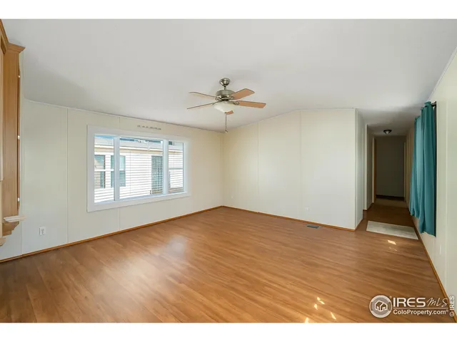 an empty room with wooden floor and a ceiling fan