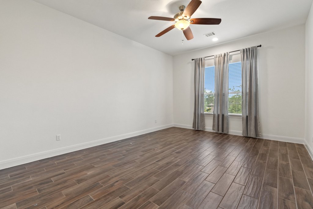 17641 Stratus Cove Dripping Springs, TX 78620 - Photo 24 of 40 an empty room with wooden floor fan and windows