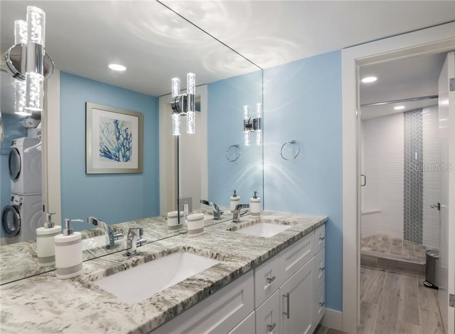 2110 Benjamin Franklin Drive, Unit 503SEA Sarasota, FL 34236 - Photo 12 of 29 a bathroom with a granite countertop double vanity sink a mirror and a shower