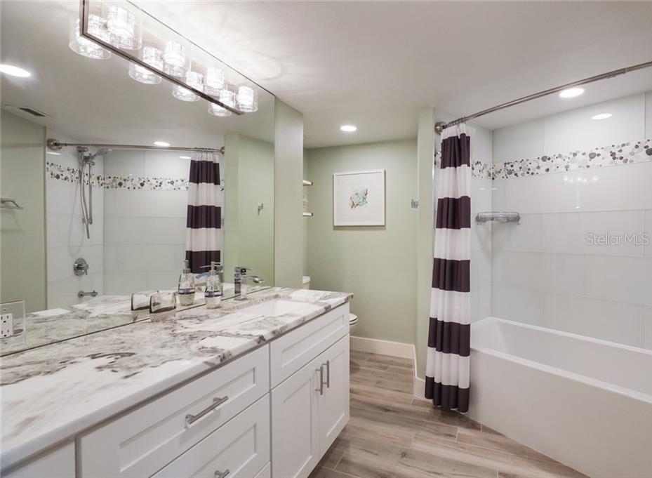 2110 Benjamin Franklin Drive, Unit 503SEA Sarasota, FL 34236 - Photo 15 of 29 a bathroom with a sink double vanity granite tub shower and a mirror