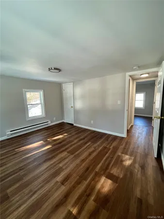 a view of empty room with window and wooden floor