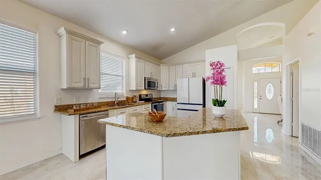 a kitchen with granite countertop kitchen island stainless steel appliances a sink stove and refrigerator