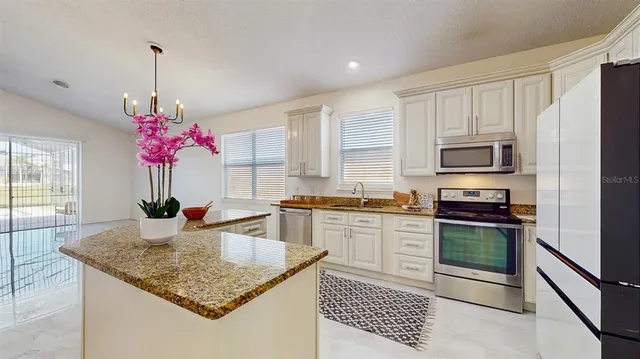 a kitchen with stainless steel appliances granite countertop a kitchen island a stove and a sink