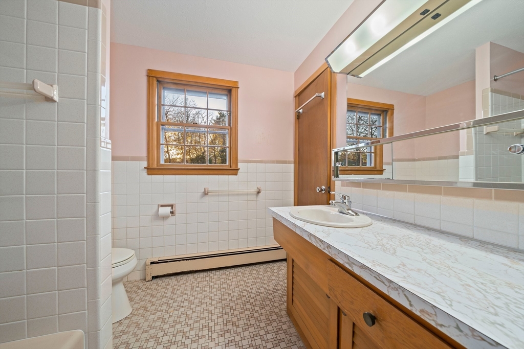 59 Windsor Road Weymouth, MA 02190 - Photo 17 of 39 a bathroom with a granite countertop sink a toilet a mirror and shower