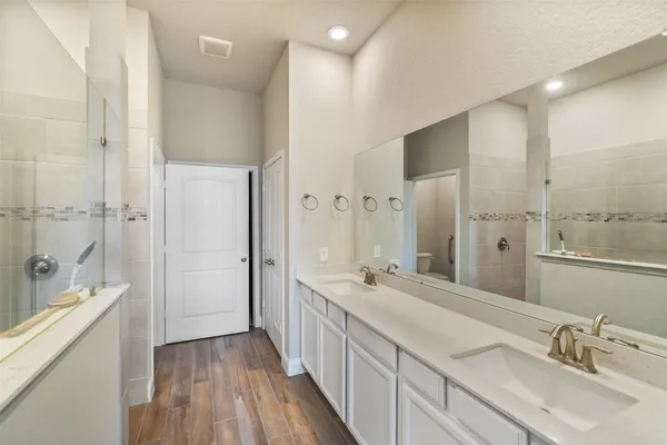 a spacious bathroom with a double vanity sink a large mirror and shower