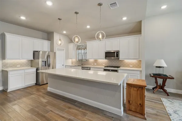 a kitchen with kitchen island a counter top stainless steel appliances and cabinets