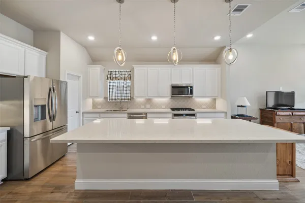 a large kitchen with stainless steel appliances a large counter top oven and cabinets