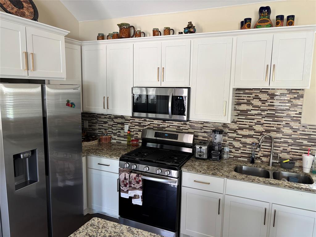 343 North Morris Street Gainesville, TX 76240 - Photo 4 of 18 a kitchen with granite countertop white cabinets and stainless steel appliances