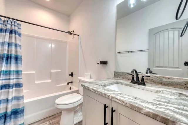 a bathroom with a granite countertop sink toilet and shower