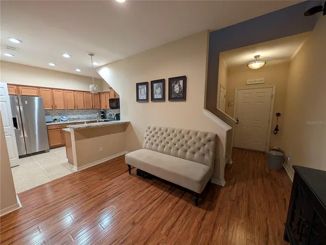 a living room with stainless steel appliances furniture and a wooden floor