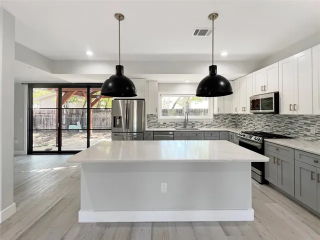 a kitchen with stainless steel appliances granite countertop a sink a stove and a wooden floor